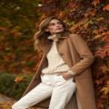 full body view of a woman in a camel wool coat ov